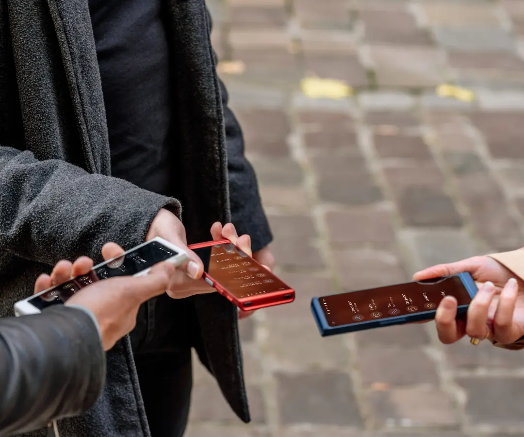 Tre venner holder glædeligt deres oversættere i hånden, er optaget af en samtale og nyder at være sammen. 